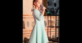маленькая девочка в красивом платье поет