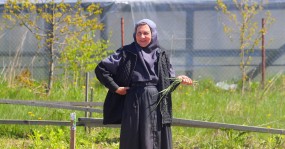 монахиня на фоне теплиц