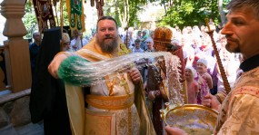 священник окропляет святой водой