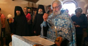 священник со свечой молится