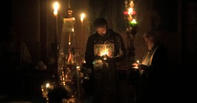 священник молится со свечой