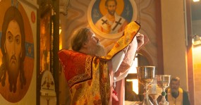духовник молится в алтаре перед Чашами