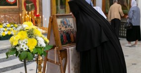 монахиня прикладывается к иконе праздника