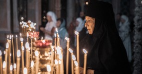 монахиня у горящих свечей
