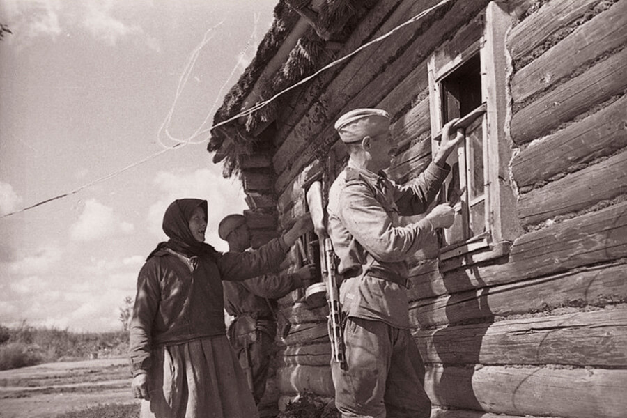 солдаты вставляют окна в хату 