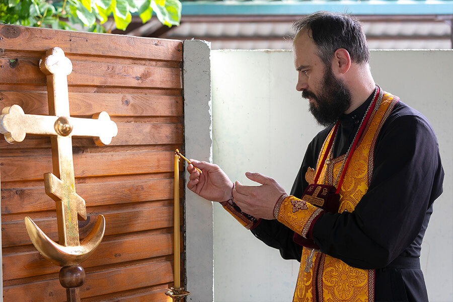 священник зажигает свечу
