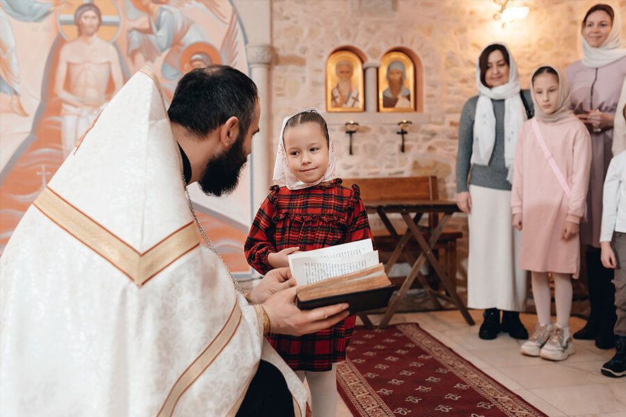 священник беседует с маленькой девочкой