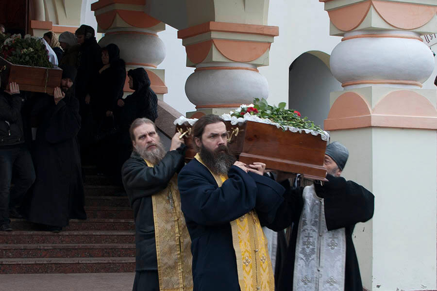 священники несут гроб