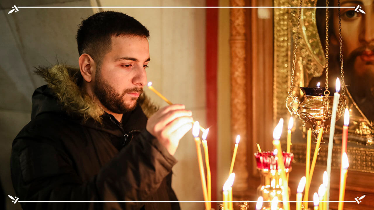 молодой человек зажигает свечу