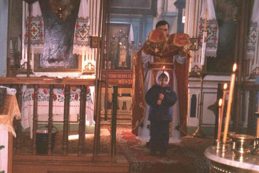 священник и ребенок со свечой 